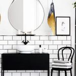 Real photo of black and white bathroom interior with a mirror, cupboard, chair and plants